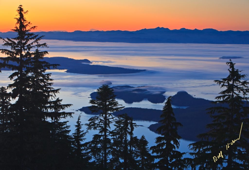 View from Vancouver Island North over Hanson Island, Stubbs Island, Malcolm Island, Donegal Head over Queen Charlotte Strait towards the British Columbia Coastal Mountains at twilight, dusk with fog banks creeping over the islands, British Columbia, Canada.